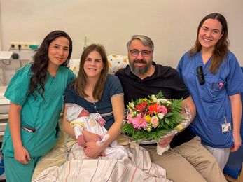Im Eltern-Kind-Zentrum des Klinikums Hanau stehen Hebamme Selin Gündüz, Mama Antonia mit Baby Erik, Papa Robert und Assistenzärztin Anja Kaltenbach nebeneinander. Sie lächeln in die Kamera und freuen sich über die 1.000. Geburt des Jahres.